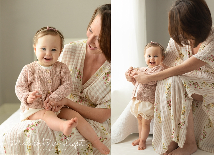 Mother and baby daughter smiling in the studio window of baby photographer in The Woodlands