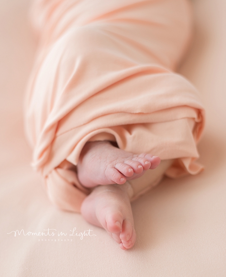 A newborn's feet wiggle free from her swaddle as she sleeps. 