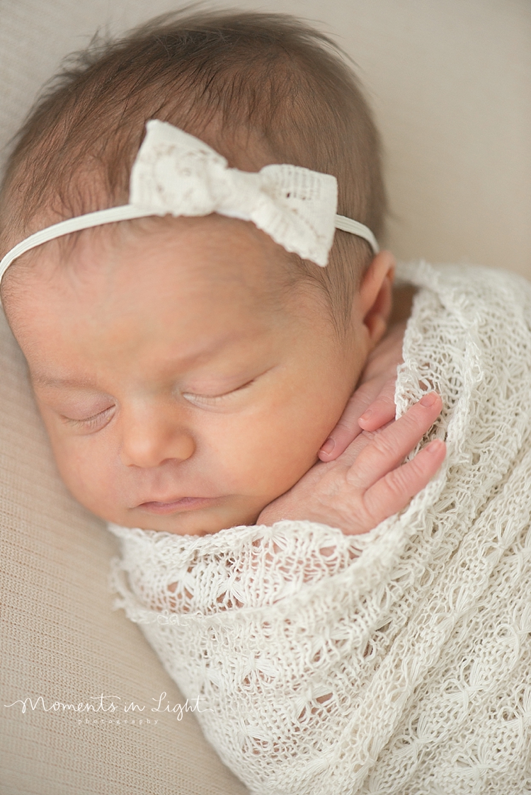 A baby is wrapped in a white lace blanket while she naps. 