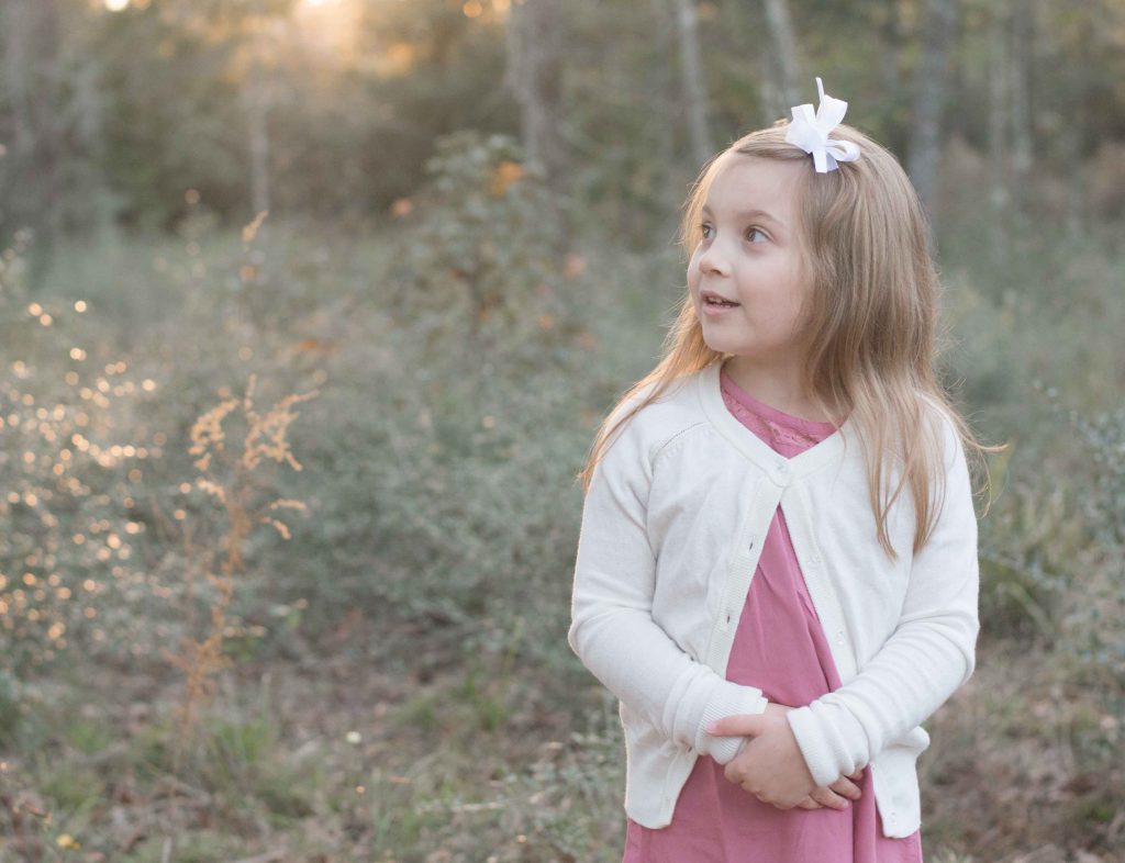 little girl with sunset behind her in a field in The Woodlands, TX