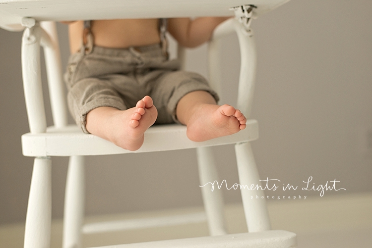 Baby boy's feet hanging off of wooden chair in a baby photography studio in Houston