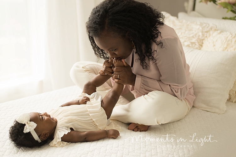 A baby and family photographer captures a mom kissing her baby's feet. 