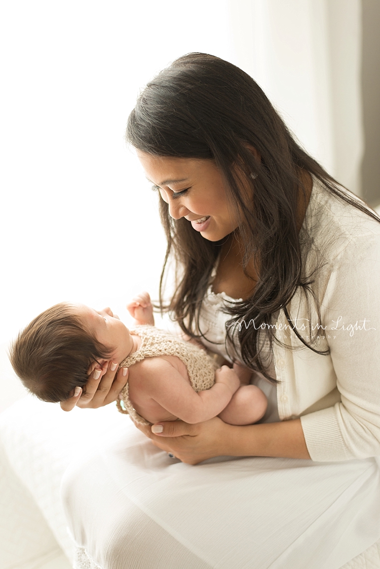 A woman gently holds her baby's head in her hands as she talks to her. 