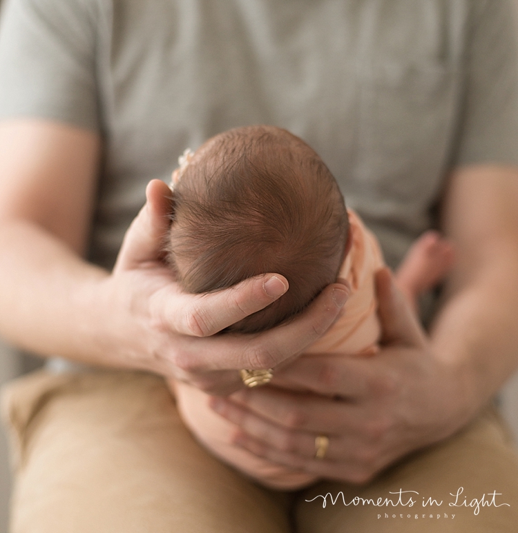 During a family with newborn photography session, a baby falls asleep in daddy's hands. 