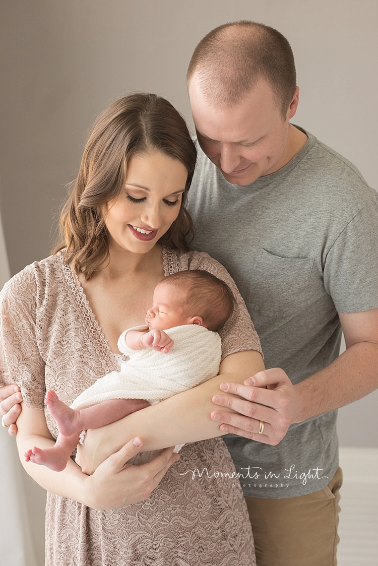 Moments In Light Photography photographs new parents as they hold their newborn daughter. 