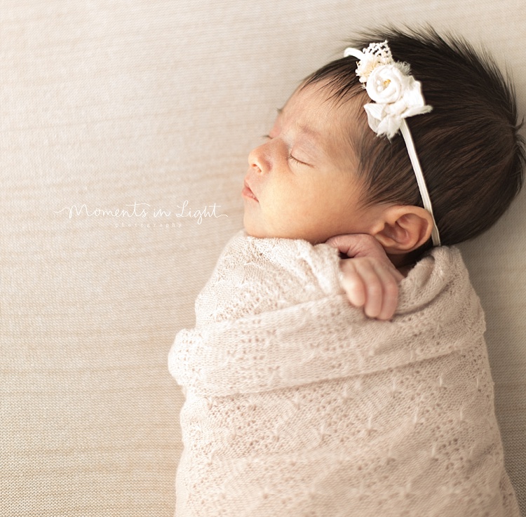 A newborn girl sleeps while swaddled. 