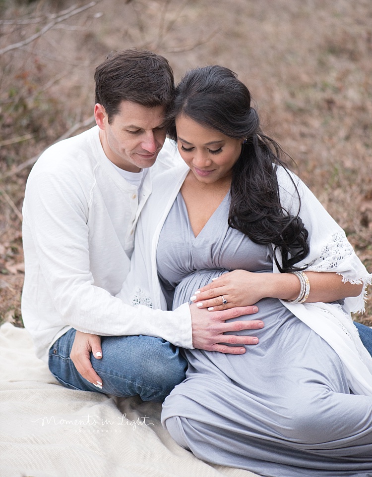 A man looks down at his pregnant wife's belly. 