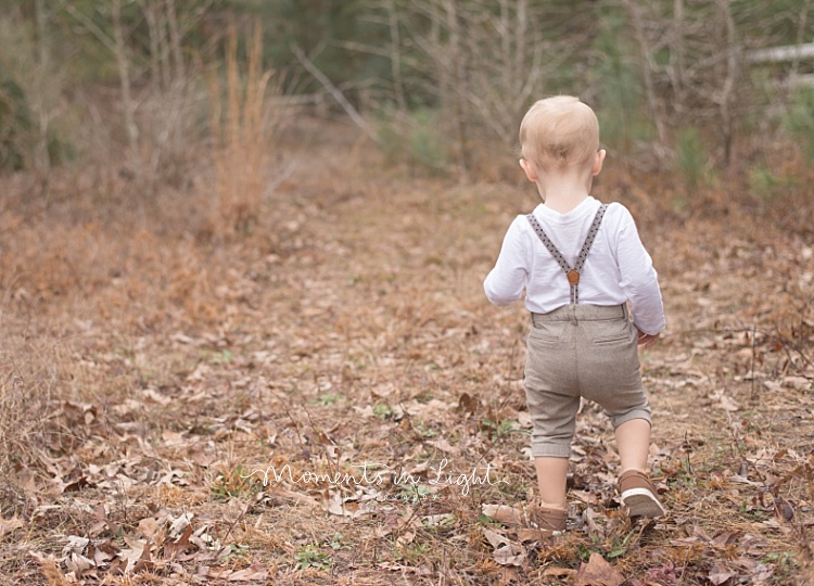 A toddler takes a walk in a field. 