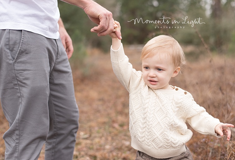 A toddler holds his dad's finger. 