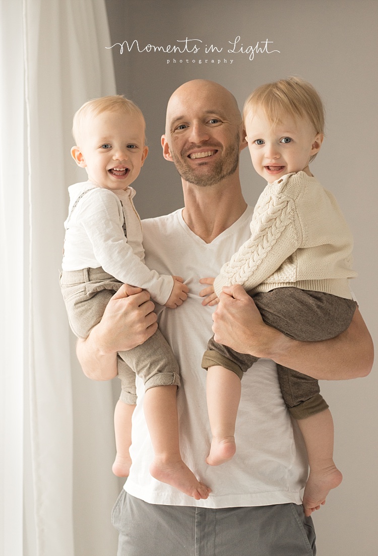 A father holds his twin baby boys. 