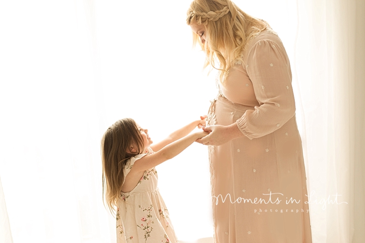 A mom holds hands with her daughter during Maternity Photos In Houston, Texas. 