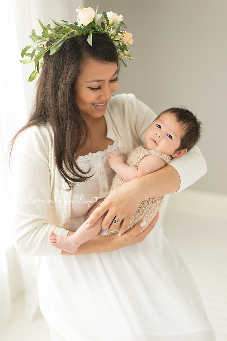 A mother cradles her baby gently as he looks around a Houston photo studio. 