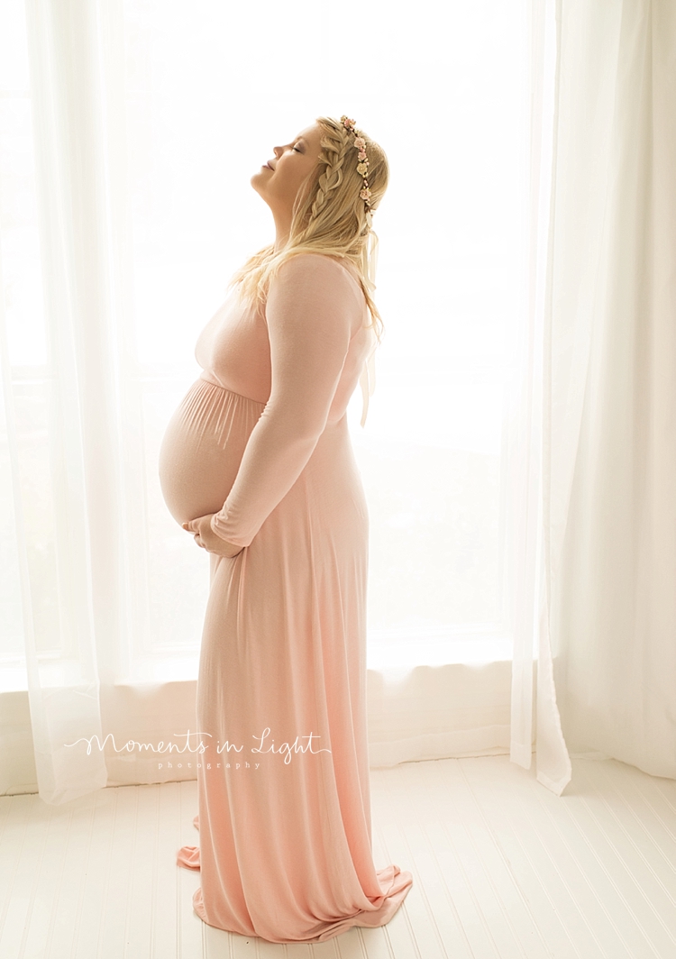 A woman looks up as she holds her large pregnant belly. 