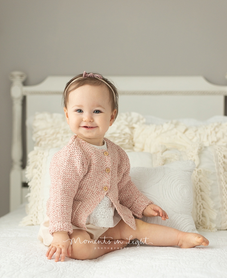 Baby girl in a pink sweater sitting on a bed by Montgomery, Texas baby photographer