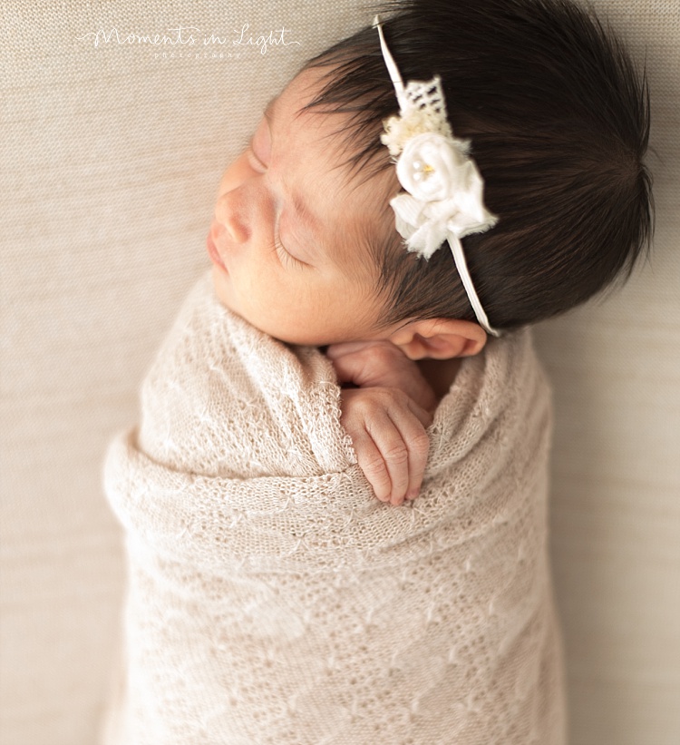 A baby girl newborn's fingers come loose from her blanket. 