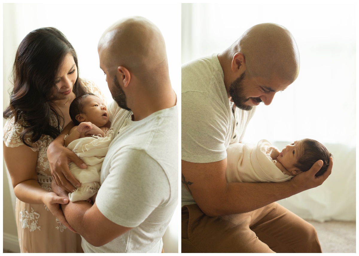 Parents holding newborn and looking into baby's eyes in photography studio in The Woodlands