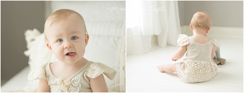 A red headed baby in a lace dress sits on a floor and plays. 