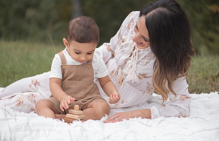 Mother in floral print dress playing with baby son in a Houston field