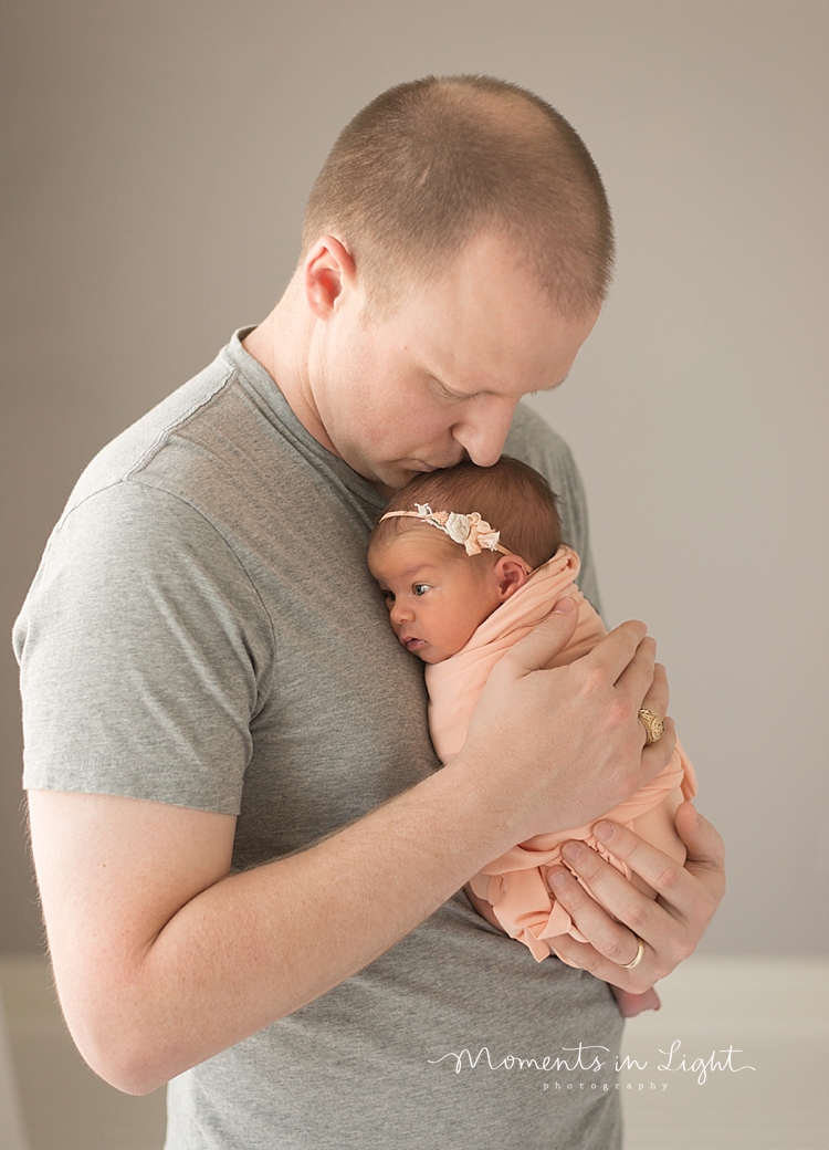 A newborn sleeps on her dad's chest during their family with newborn photography session. 