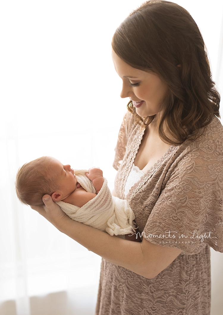 A mother holds her newborn in front of her to look at her. 