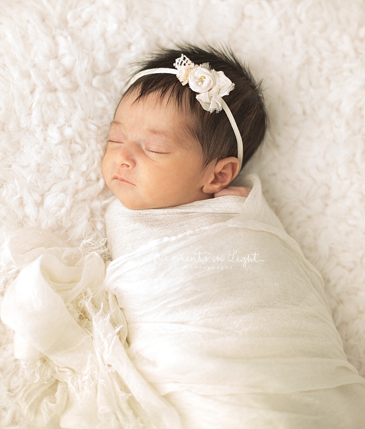 A baby sleeps on a white, fluffy blanket. 