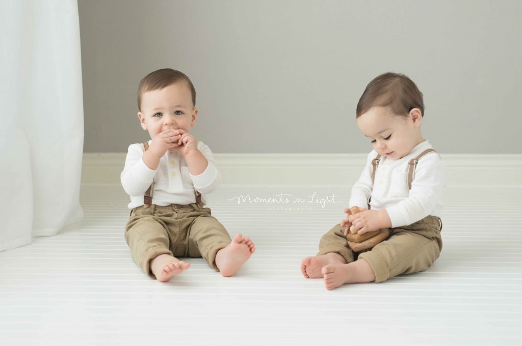 twin one year old boys sitting together in photo studio in The Woodlands, TX