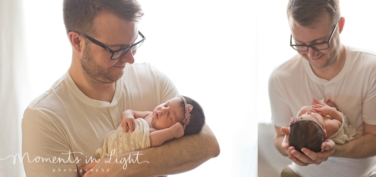 Father smiling down at baby daughter in window of Houston newborn photography studio 