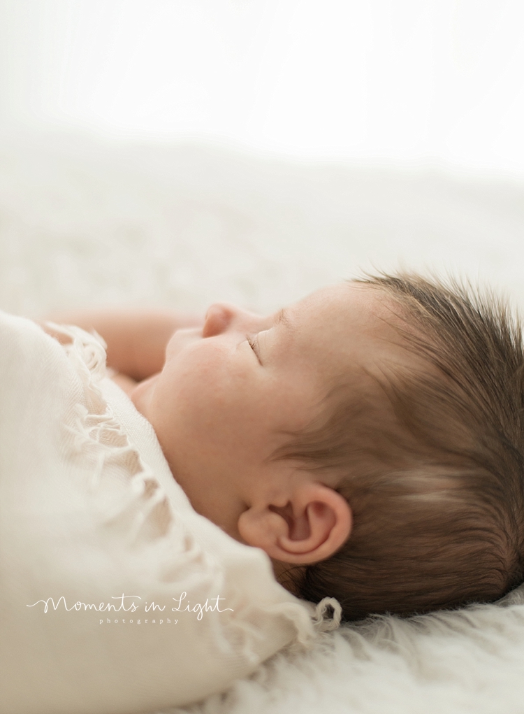 A baby sleeps peacefully during a newborn baby photography session with Moments In Light Photography. 