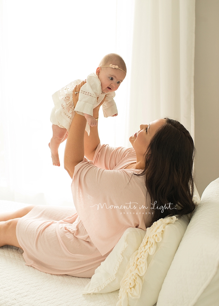 A baby photographer in Houston captures a mom holding her baby up in the air. 