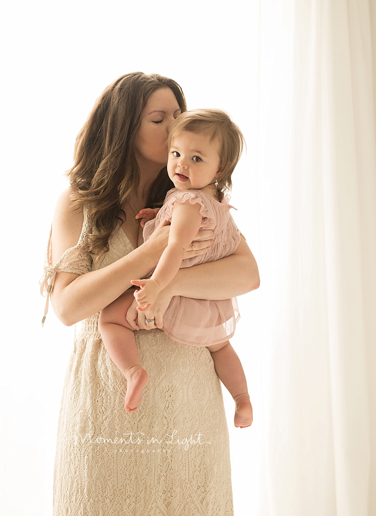 A mom kisses her baby during a session with baby photographer, Moments In Light Photography. 