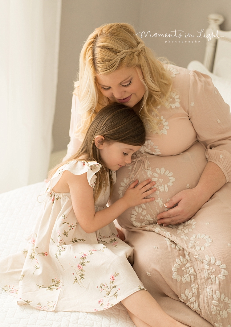 A little girl touches her mom's belly during their Maternity Photos In Houston, Texas with Moments In Light Photography.