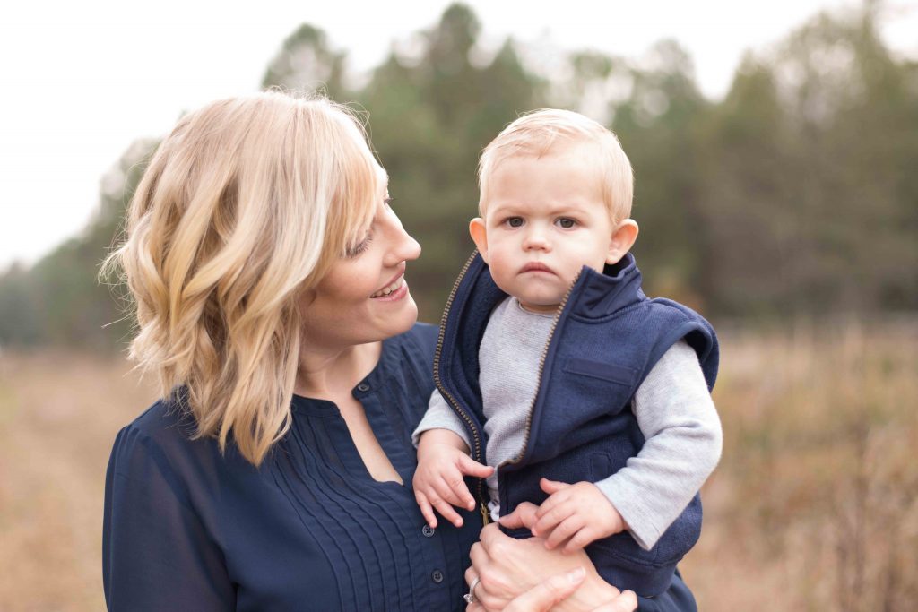 mom holding her baby boy and smiling in a field in Montgomery, TX