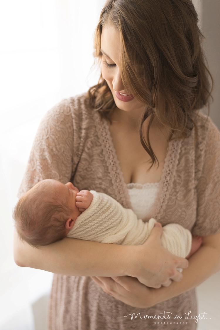 A mother cradles her baby during a photo session with Moments In Light Photography. 