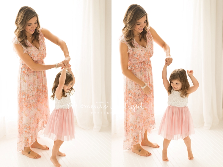 A mother twirls her daughter while dancing during a session with Moments In Light Photography. 