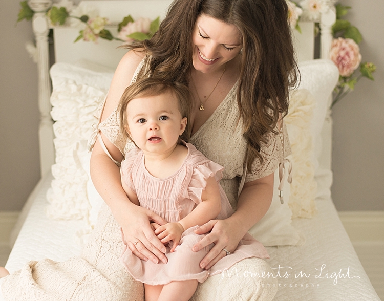 Moments In Light Photography captures a baby girl as she sits on her mom's lap. 