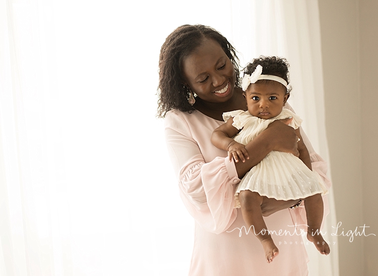 Moments In Light Photography captures a mom holding her baby in front of her. 