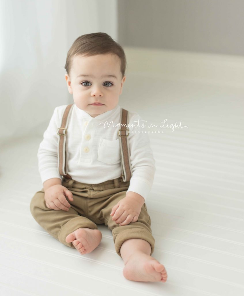 one year old little boy wearing cute outfit sitting by window in photo studio in The Woodlands, TX