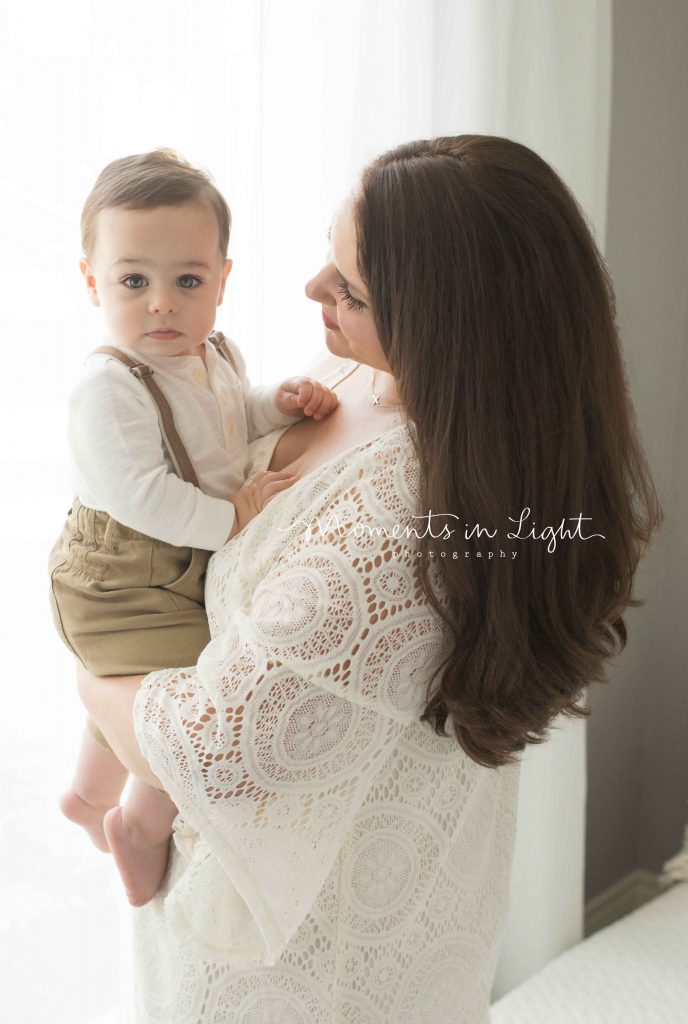 mom holding baby boy by window with big hazel eyes