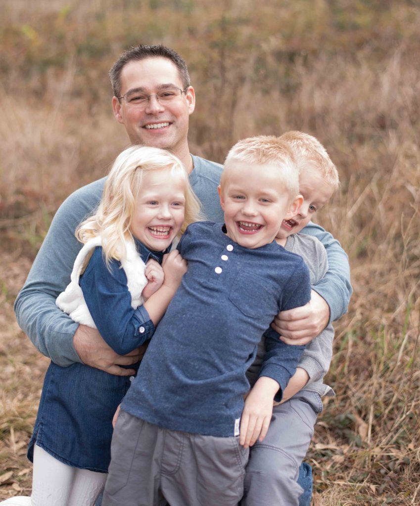 dad hugging triplets in a field in Montgomery, TX