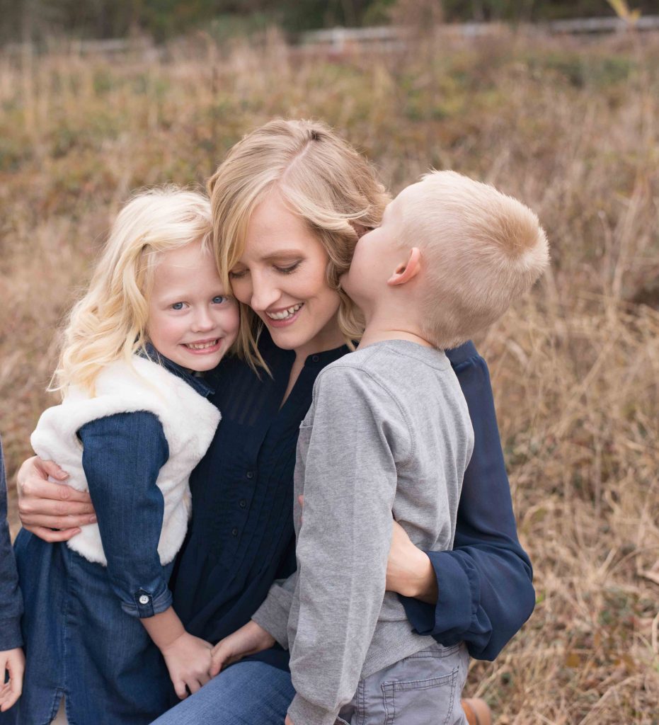 mom hugging two young children and smiling in a field in Montgomery, TX