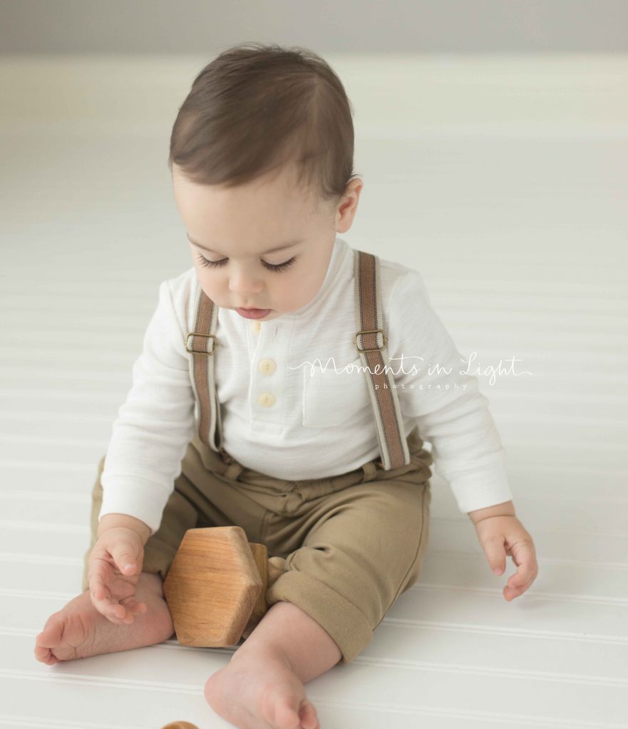 baby boy playing with an organic wooden toy in photo studio in The Woodlands, TX