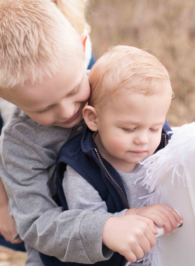 baby boy and older broth on a rocking horse in a field in Montgomery, TX