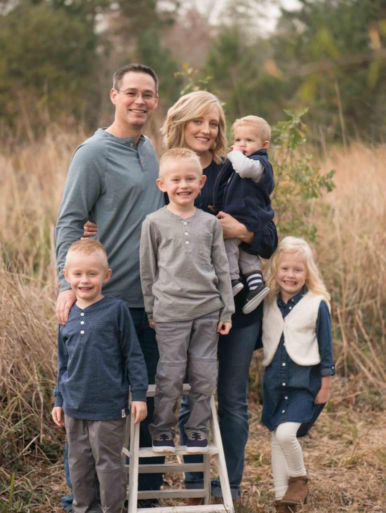 family with four children smiling in a field in Montgomery, TX