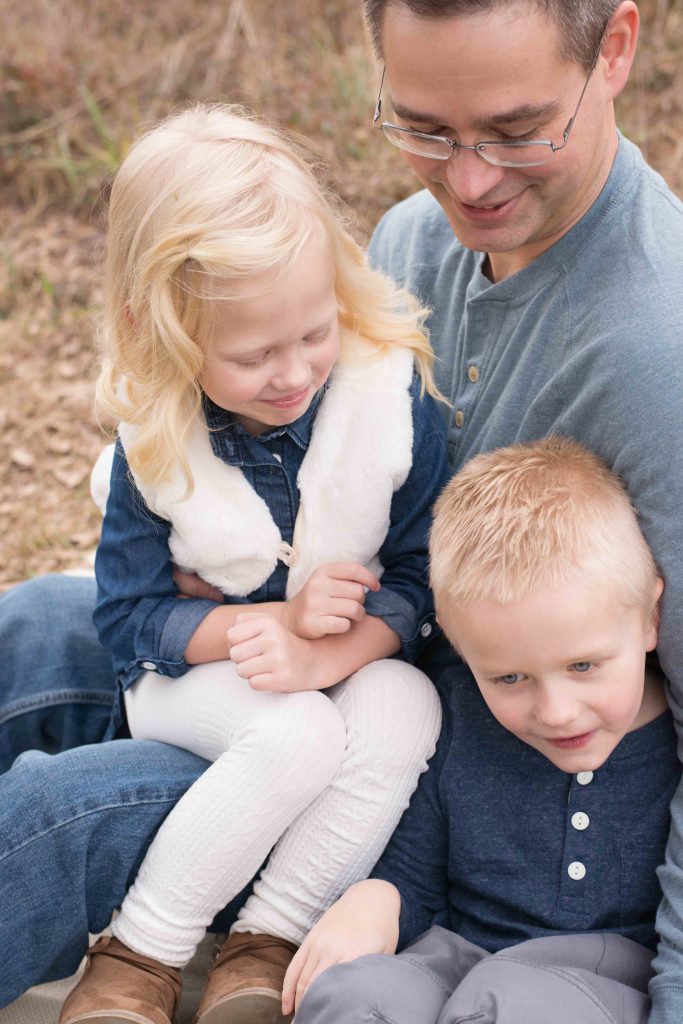 dad holding son and daughter in his lap 