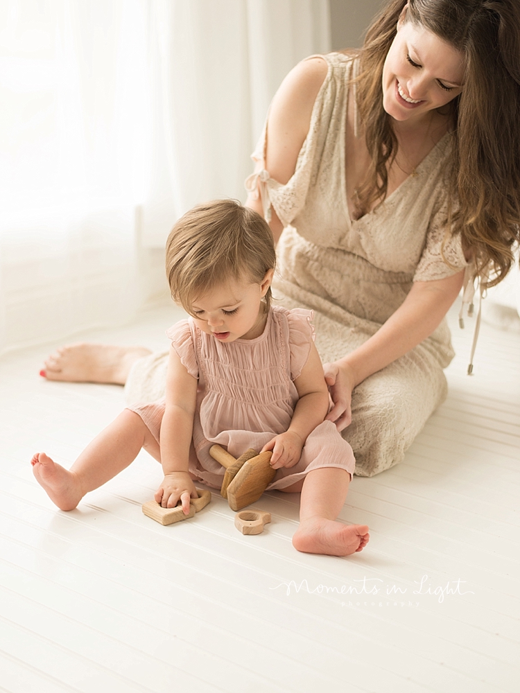 Baby sits on the floor to play during a session with Moments In Light Photography. 