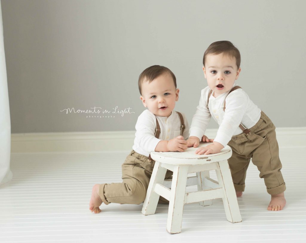 one year old twin boys playing with white still in photo studio in The Woodlands, TX