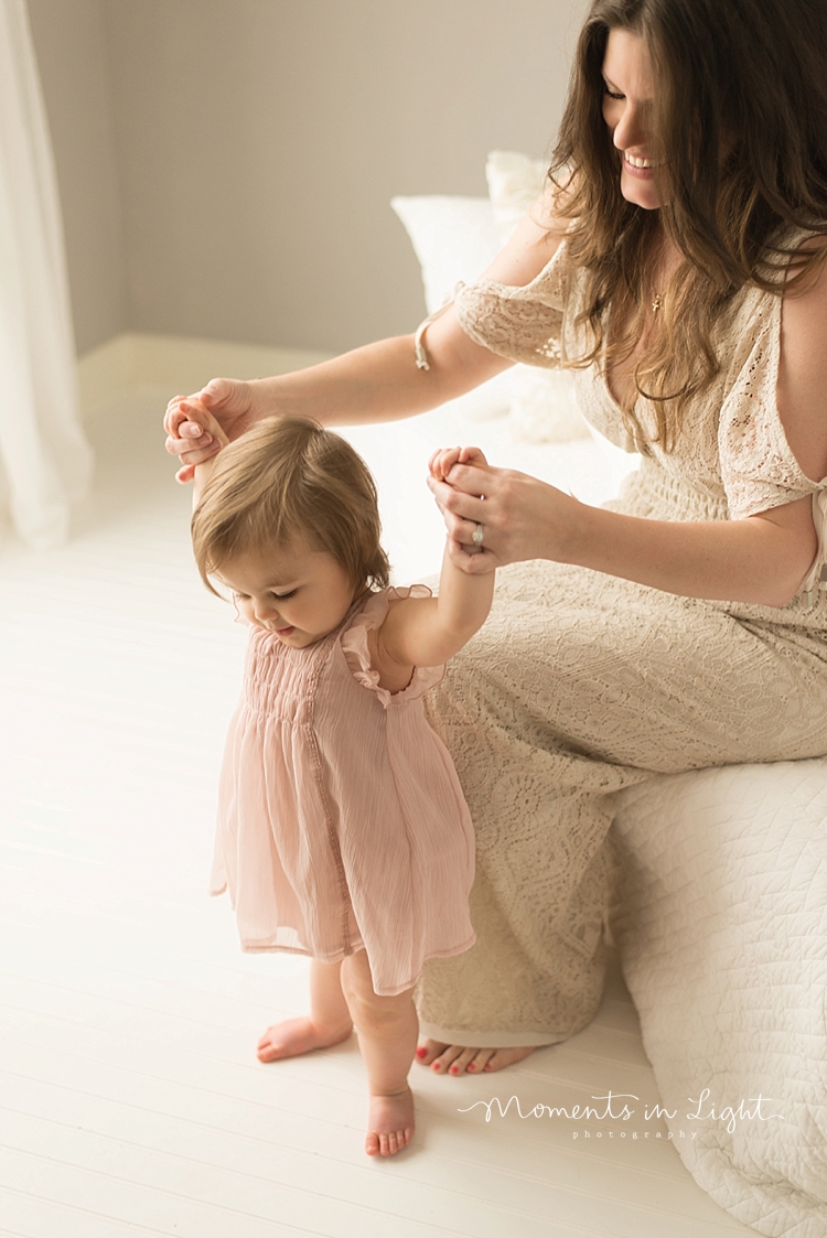 A mother holds her baby's hands to help her walk. 