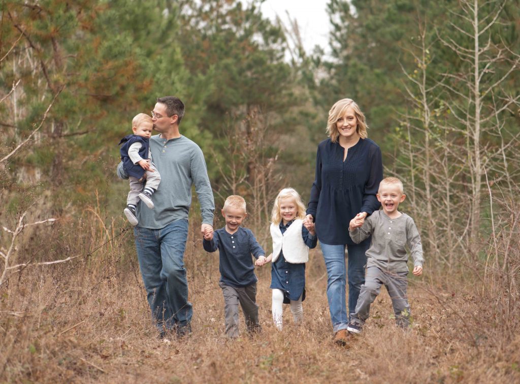 family of 6 holding hands and walking in a field in Montgomery, TX